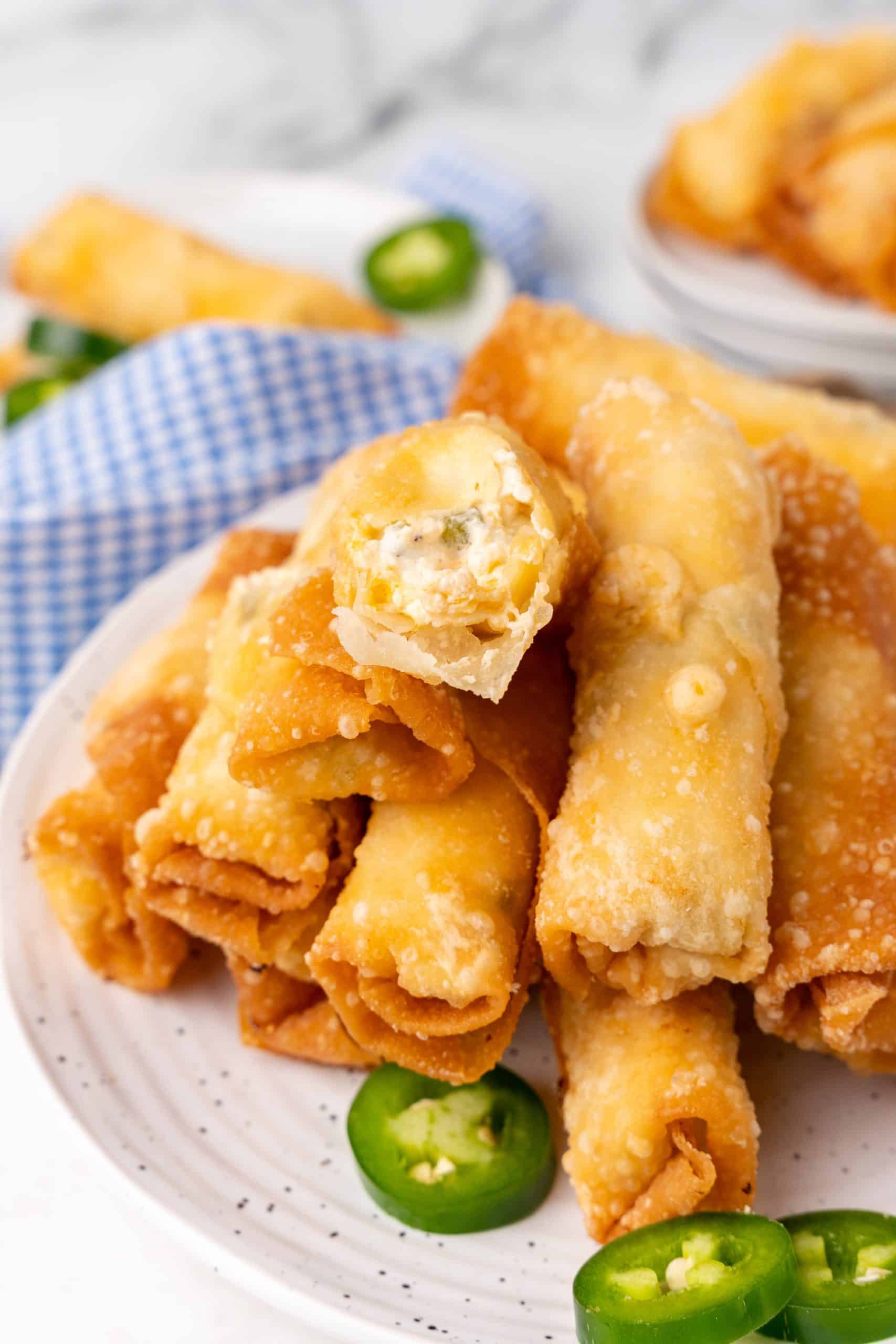 jalapeno popper egg rolls stacked on small white plates