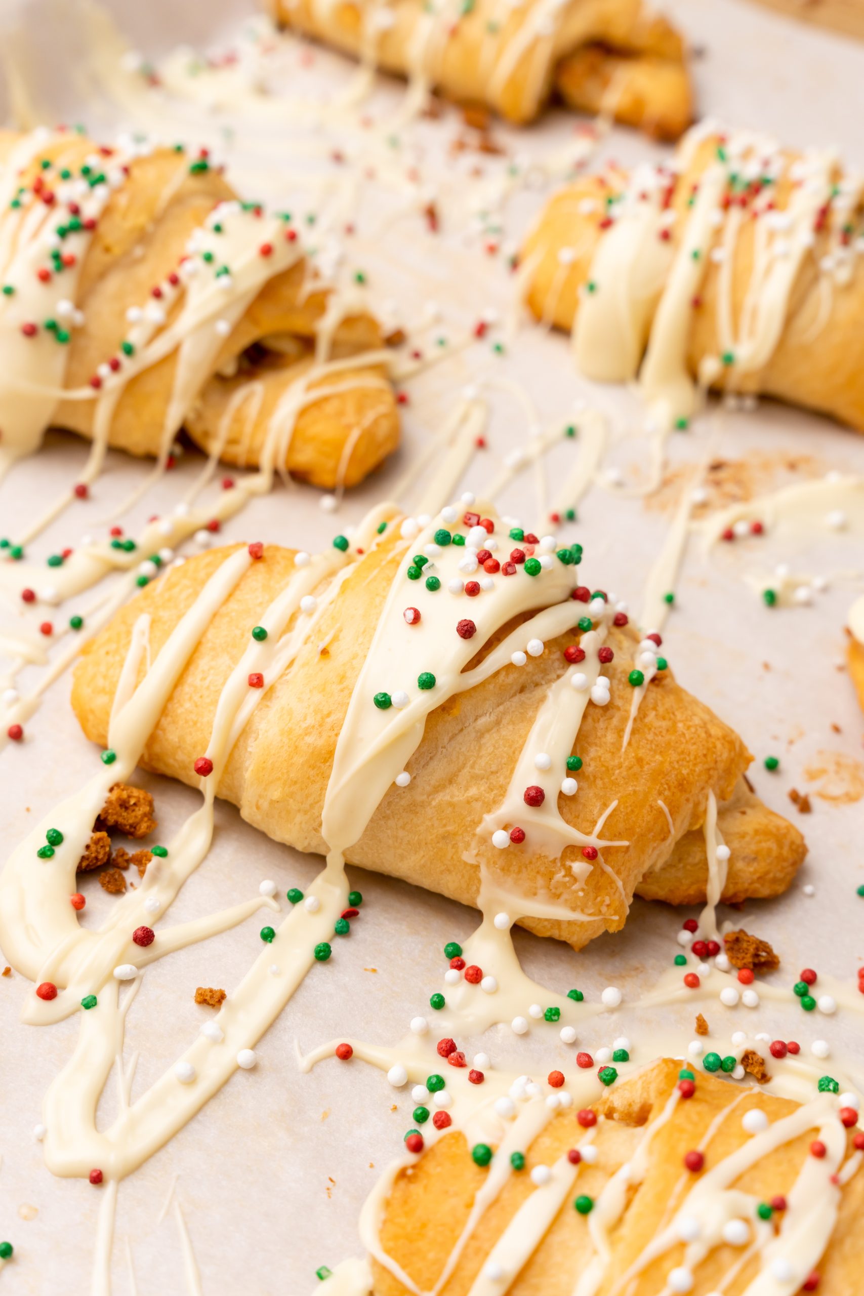sprinkle topped white chocolate gingerbread crescent rolls on a piece of parchment paper