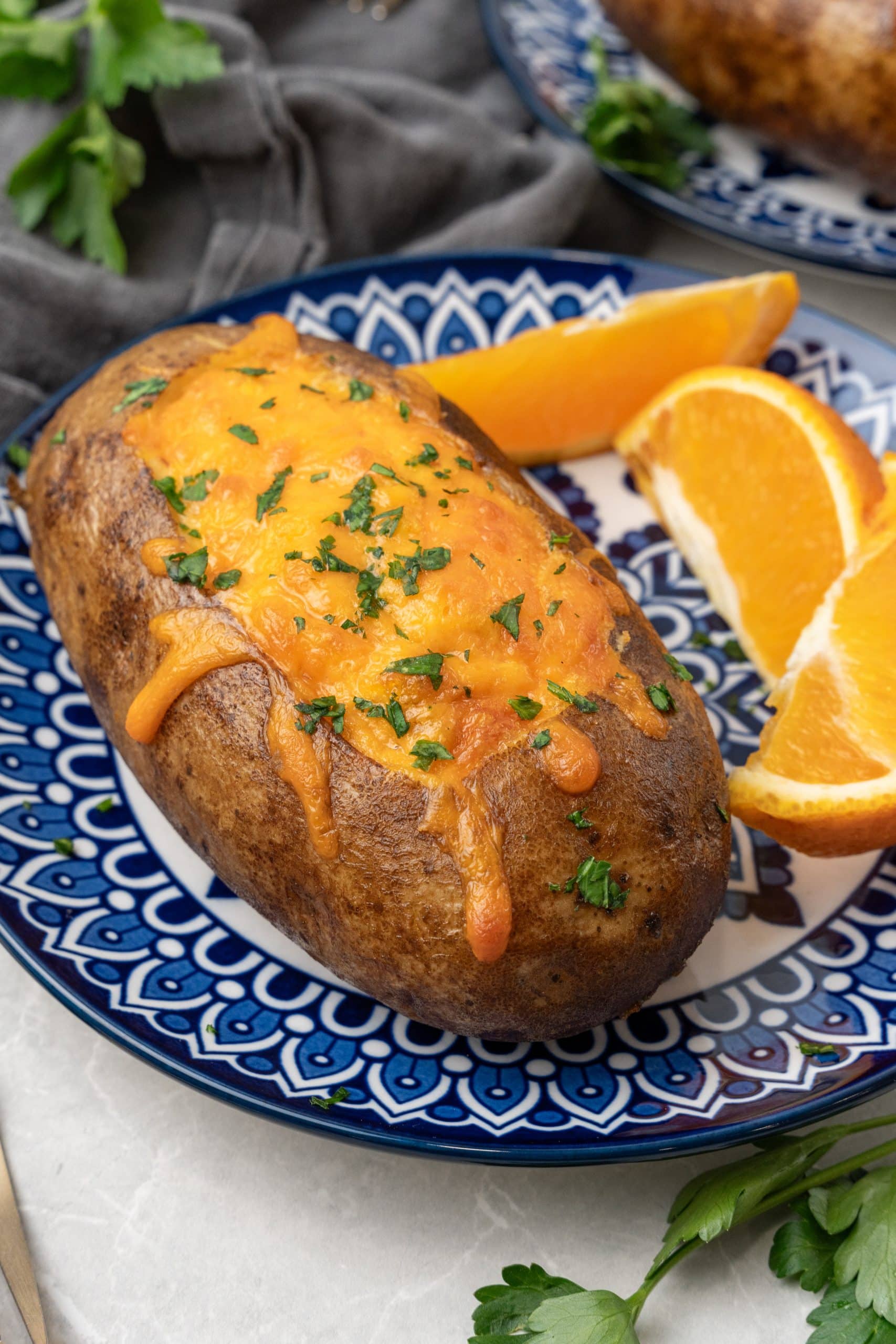 a twice baked breakfast potatoes on a blue and white plate with orange slices on the side
