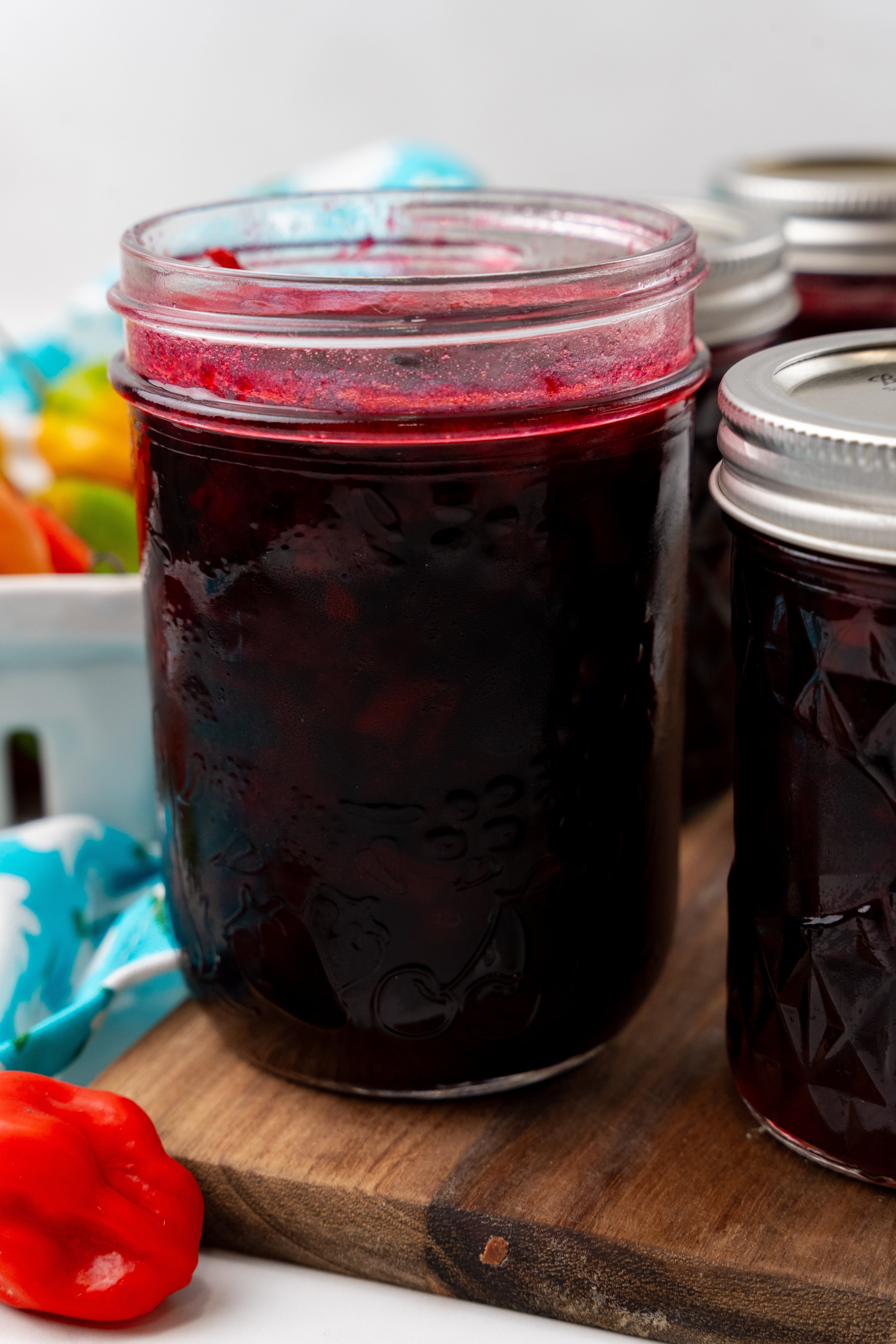 water bath canned cherry habanero jam in a small glass mason jar on a wooden cutting board