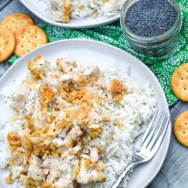 creamy poppy seed chicken casserole on two white plates with a silver fork on the side
