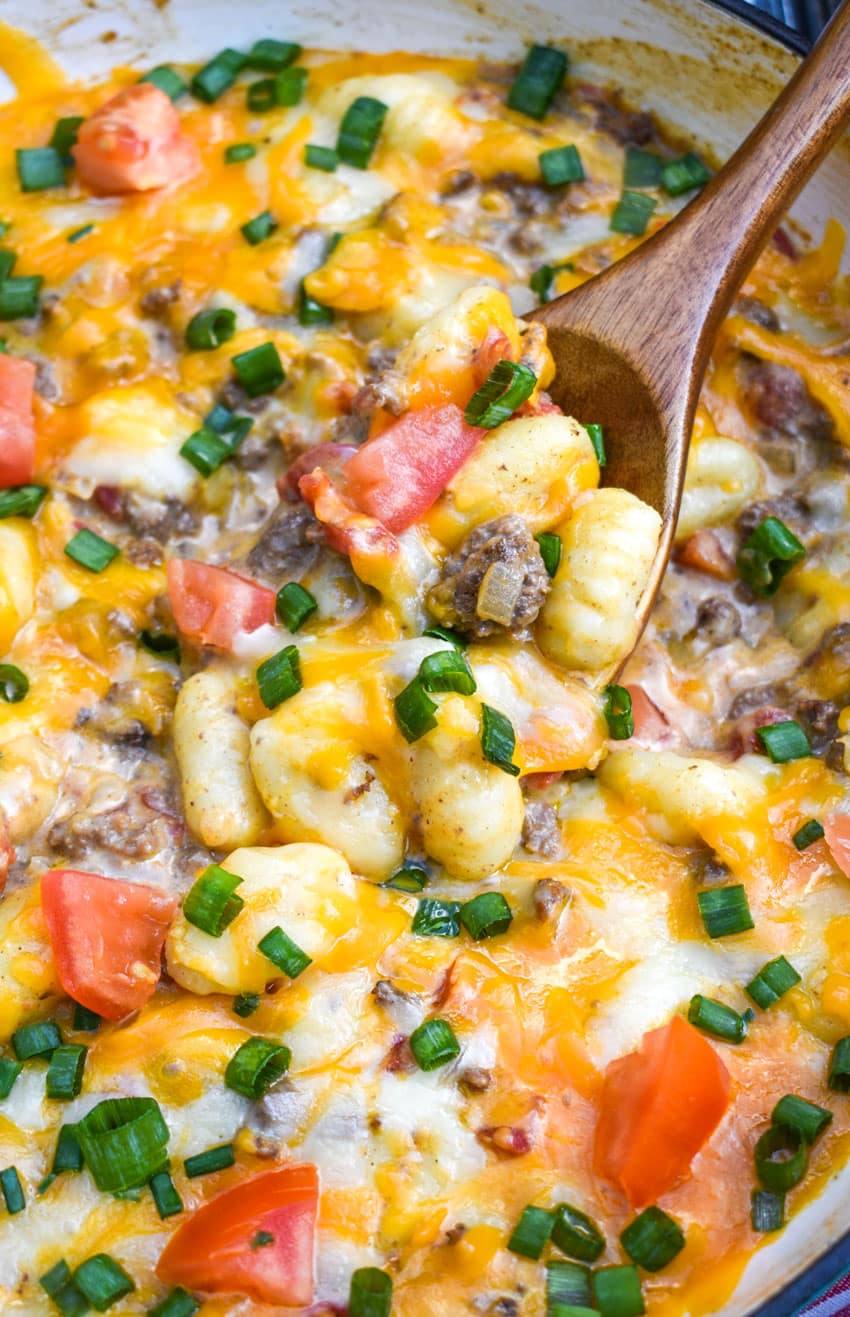 a wooden spoon in a skillet filled with cheeseburger gnocchi