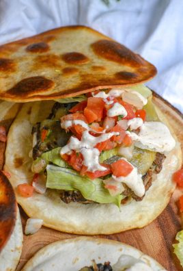 A QUESADILLA BUBRGER RESTING ON A WOODEN CUTTING BOARD