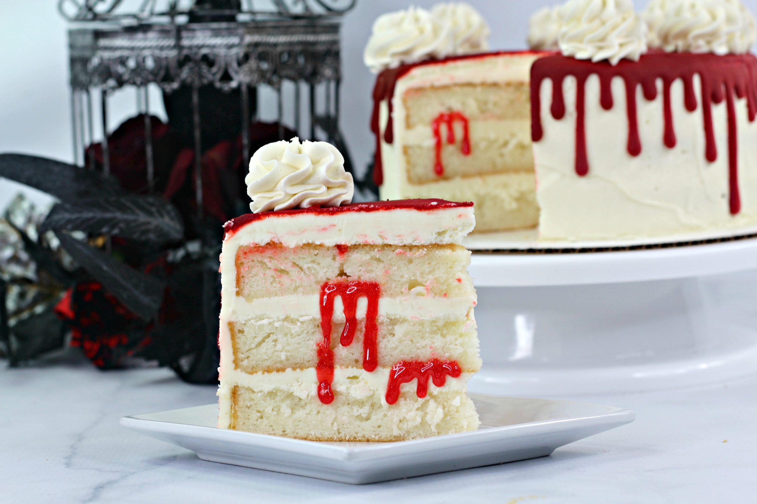 A SLICE OF BLOODY VAMPIRE LAYER CAKE ON A SMALL WHITE DESSERT PLATE