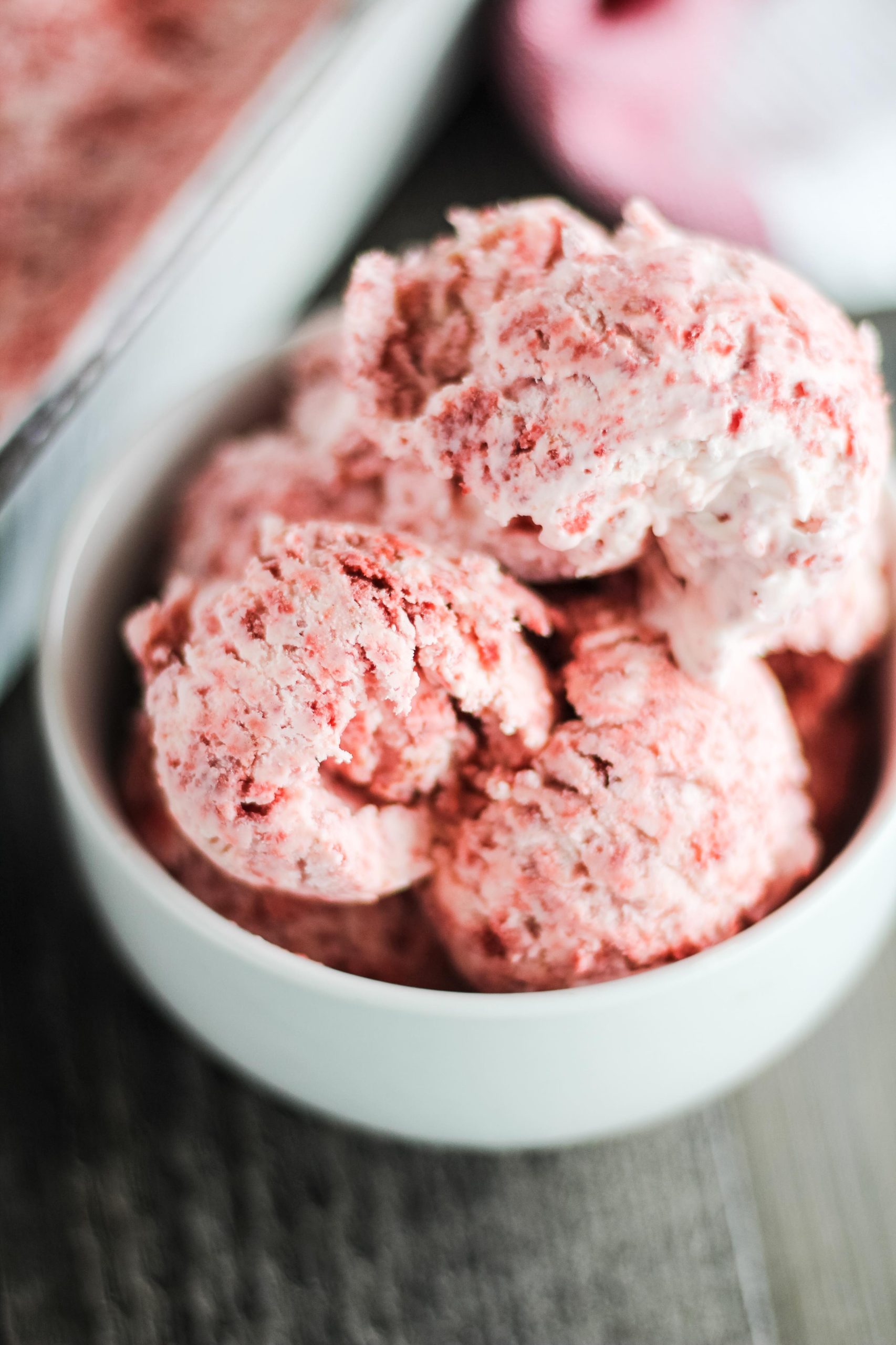scoops of no churn red velvet ice cream in a white bowl on a brown background