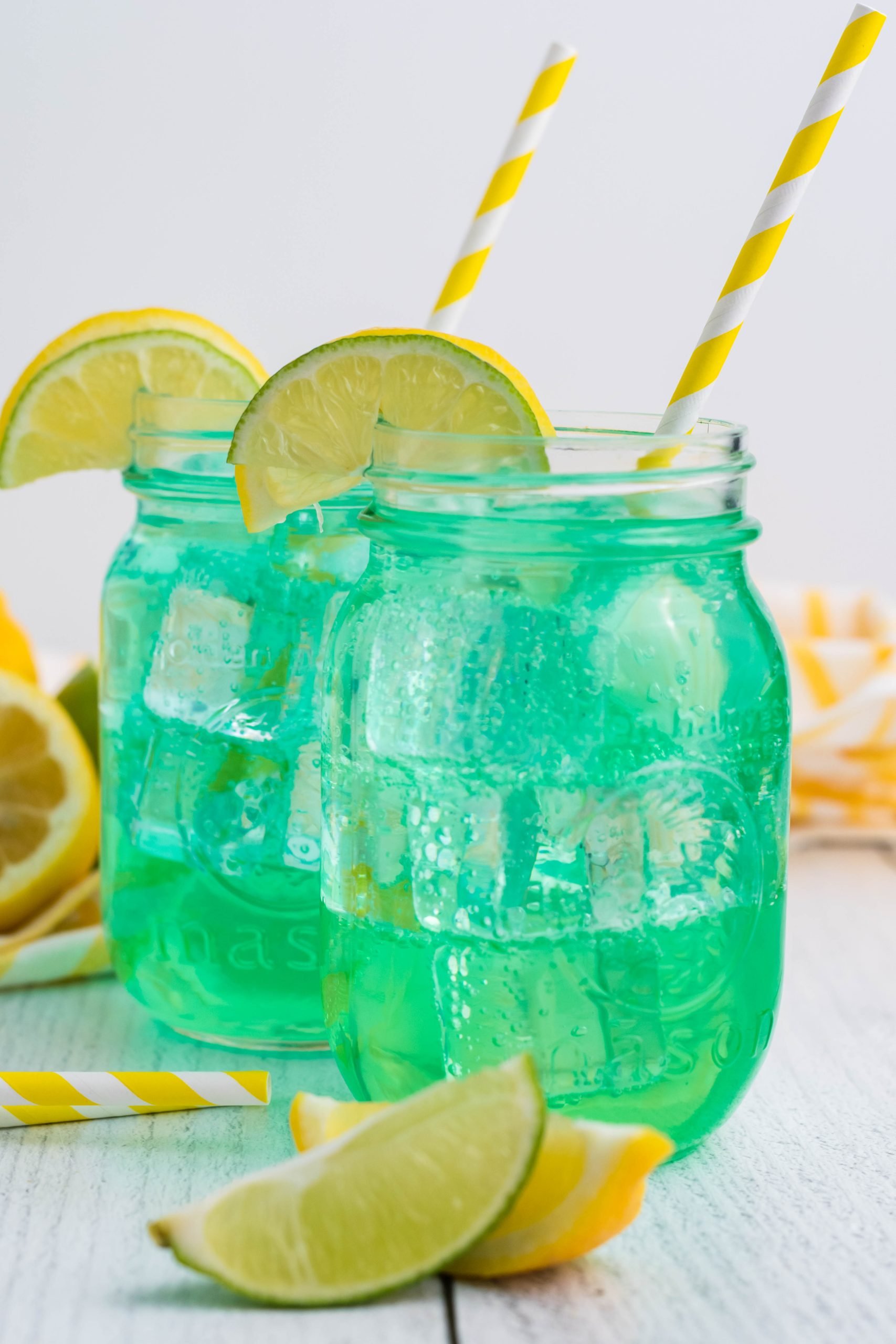 the best copycat baja blast recipe served over ice in clear glass jars with stripped yellow straw and sliced lemons for garnish