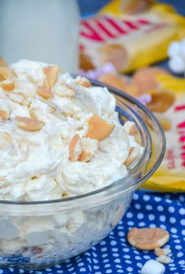 banana pudding fluff salad shown in a glass pyrex bowl topped with chopped vanilla wafers cookies