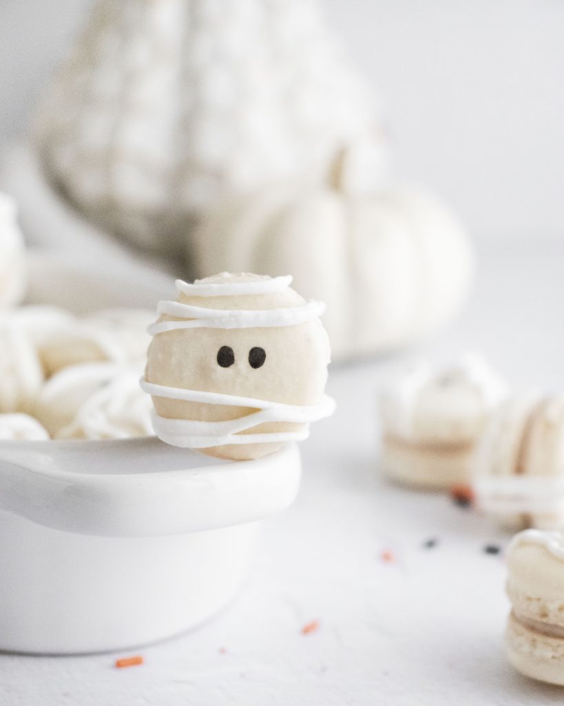 mummy macarons stacked in a white serving dish