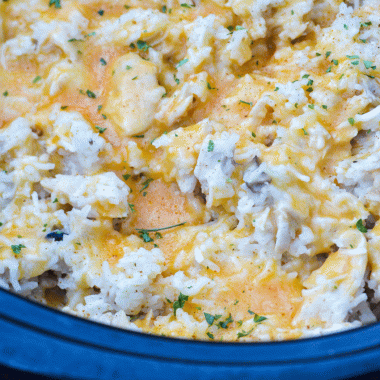crockpot pork & rice in the black bowl of a slow cooker covered with a thin layer of melted cheese