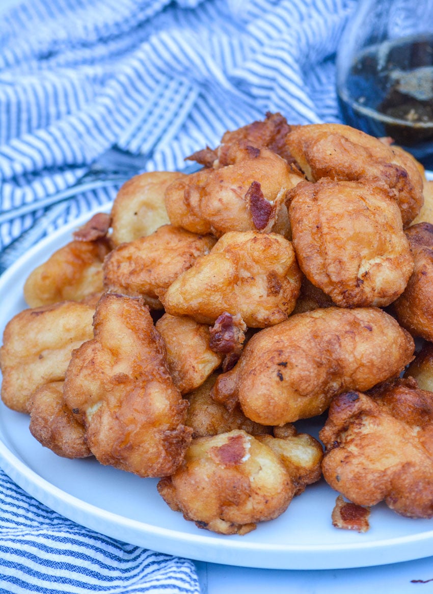pancake battered chicken nuggets on a white plate with pits of crisp crumbled bacon
