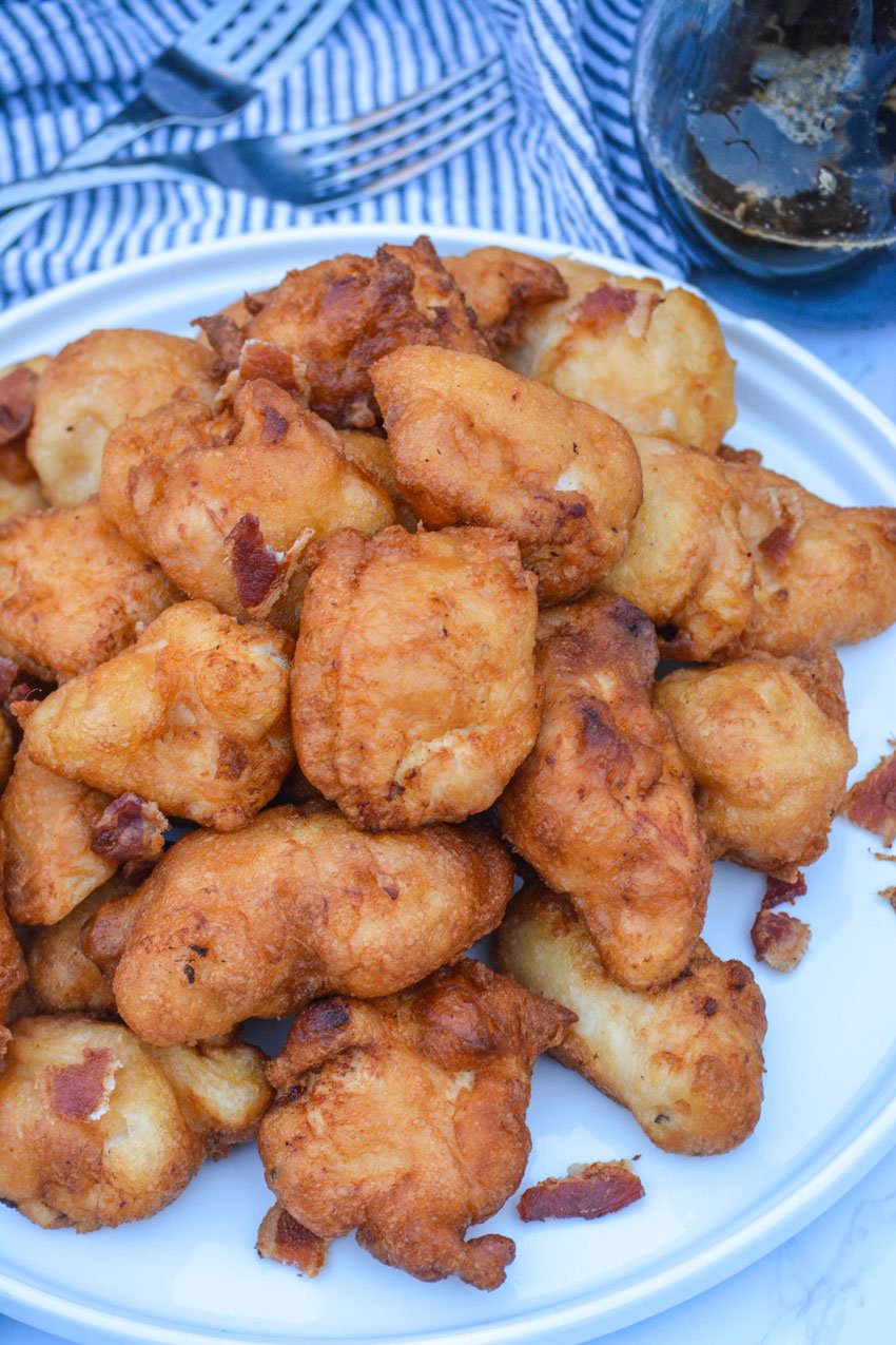 pancake battered chicken nuggets on a white plate with pits of crisp crumbled bacon