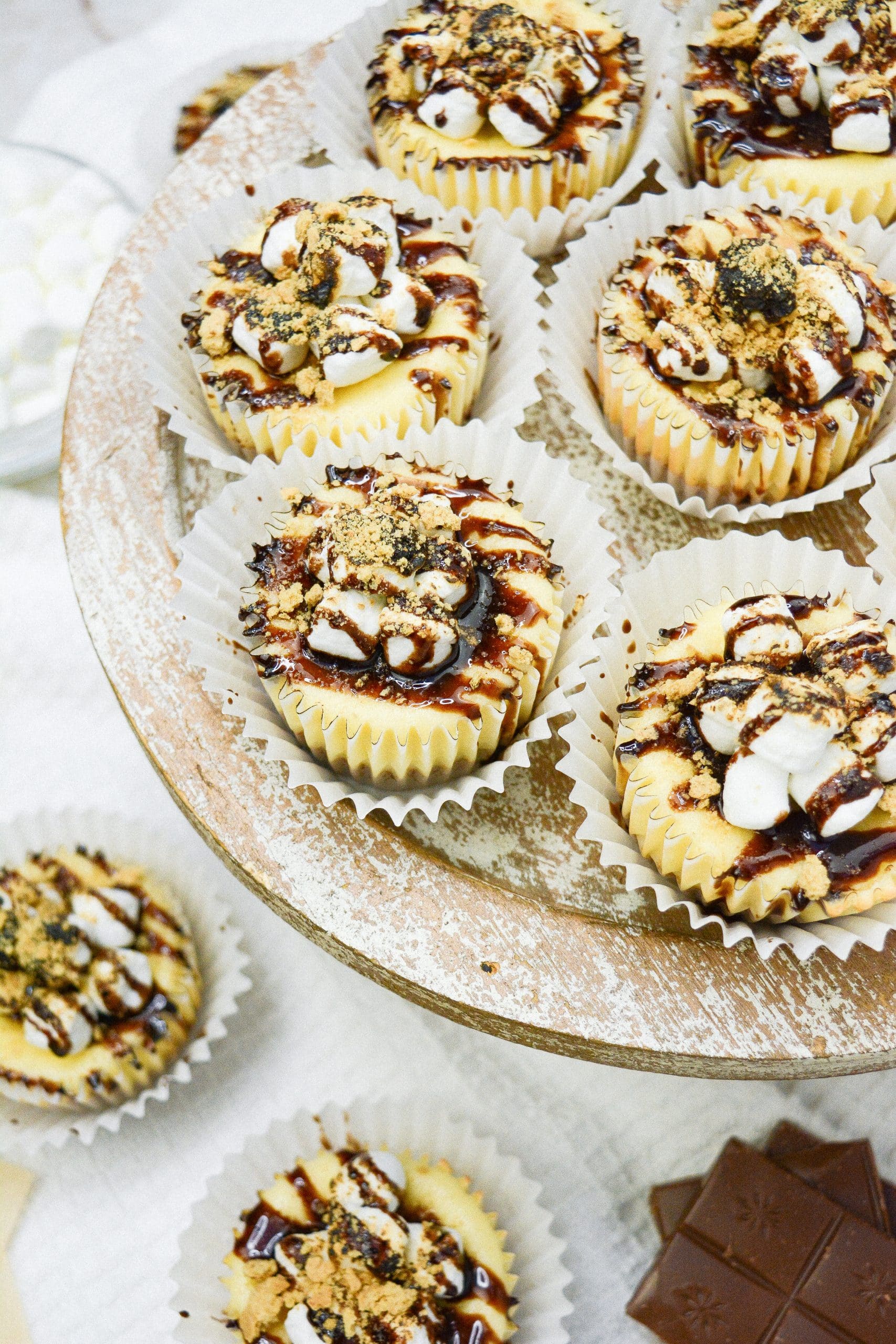 Mini s'mores cheesecakes on a wooden cake stand