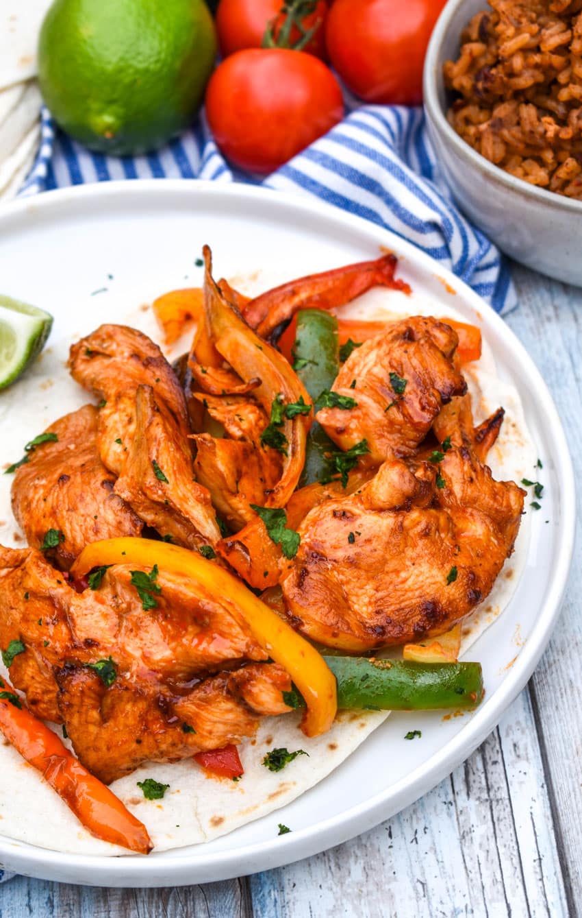 air fryer chicken fajitas over flour tortillas on a white dinner plate
